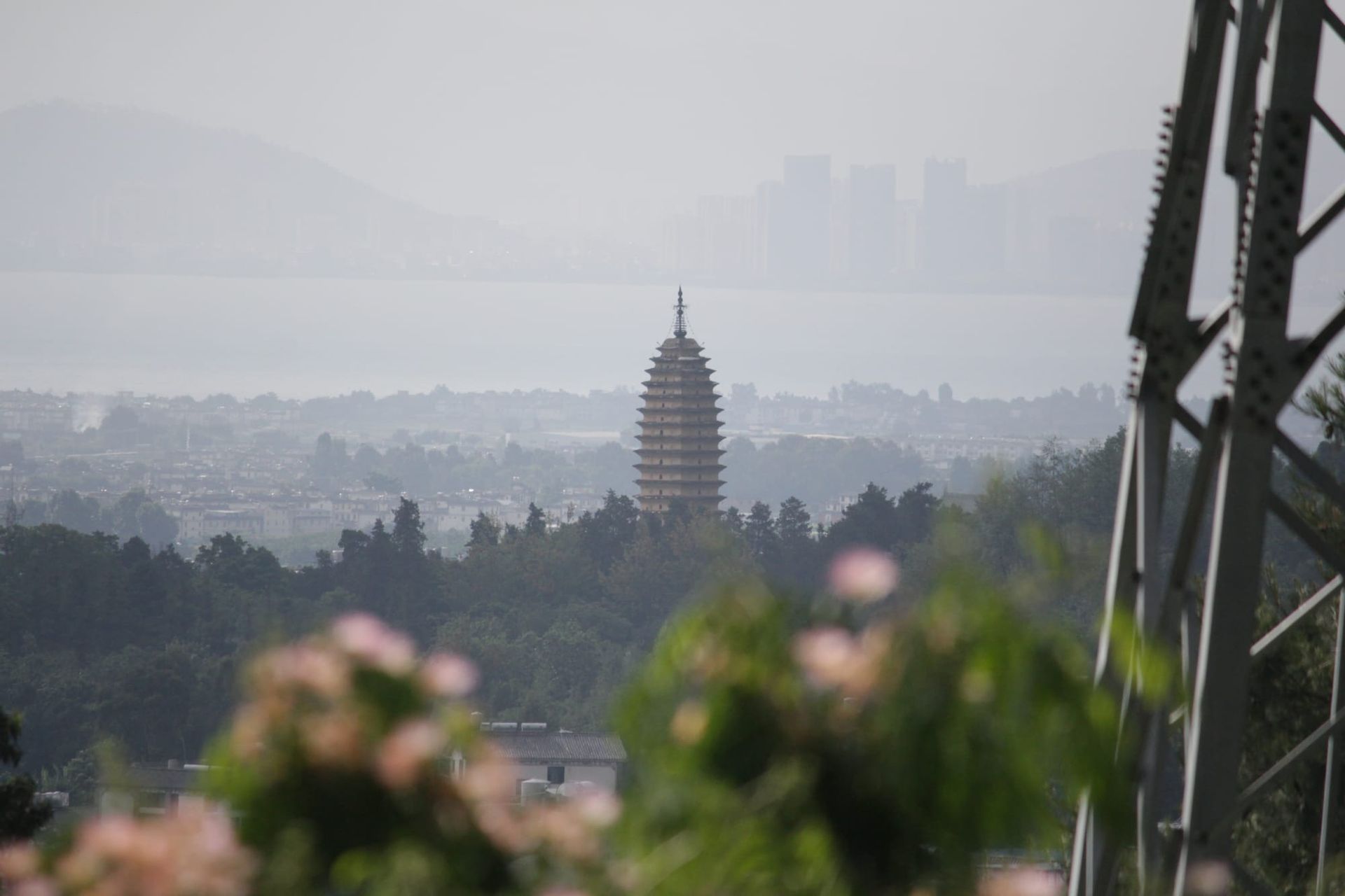 A pagoda stands tall among the city on the lakeside of Dali, viewed from afar on a chairlift going up the mountain.