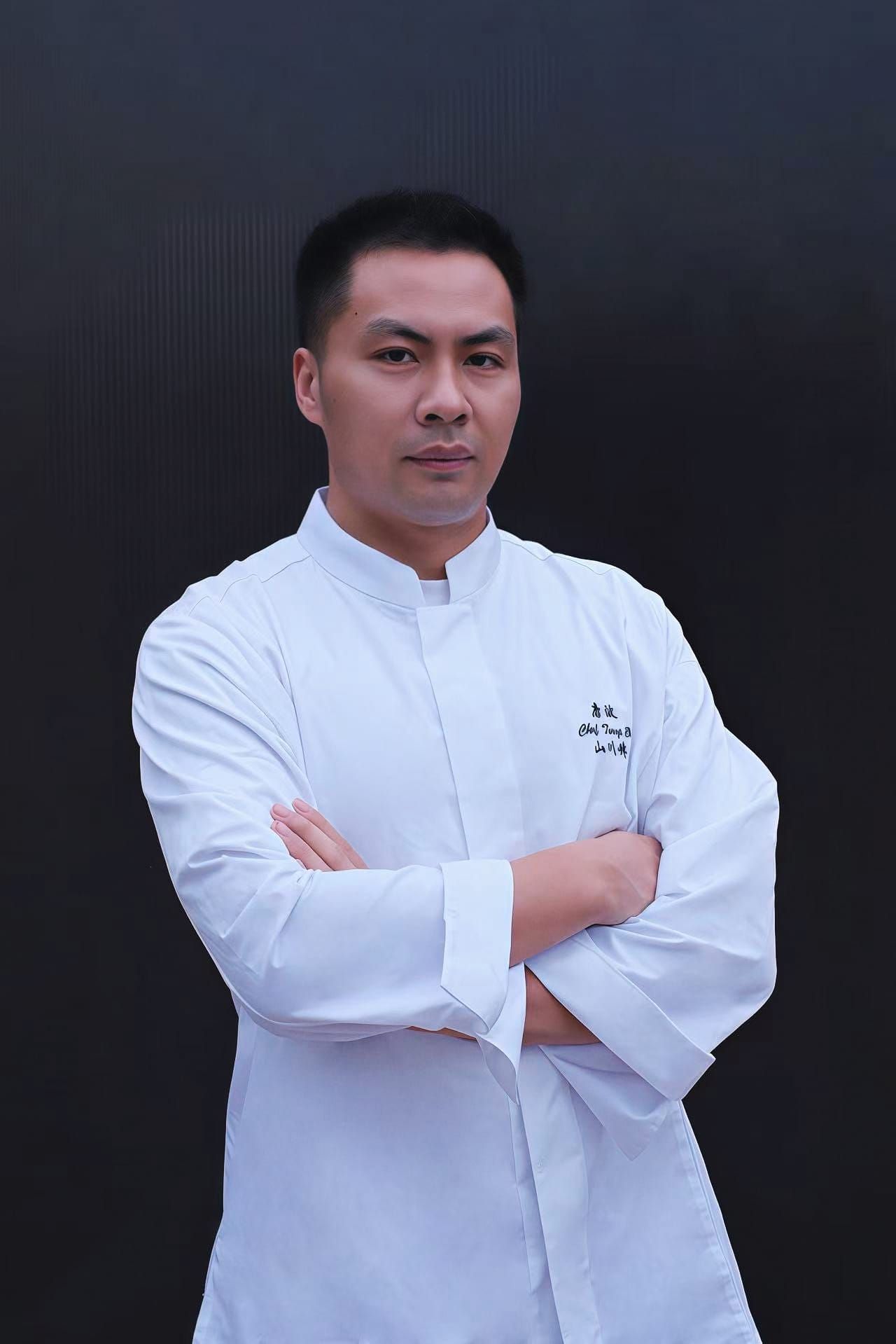 Chef Tang Bo posing for a photo with his arms crossed wearing his pure white Mount River Chef tunic.