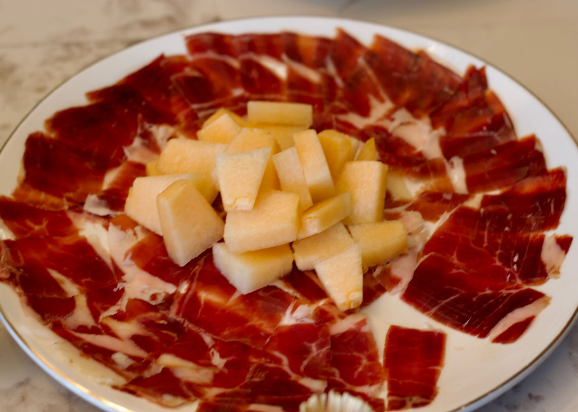 Jinhua ham surrounds cantaloupe melon on a plate. 