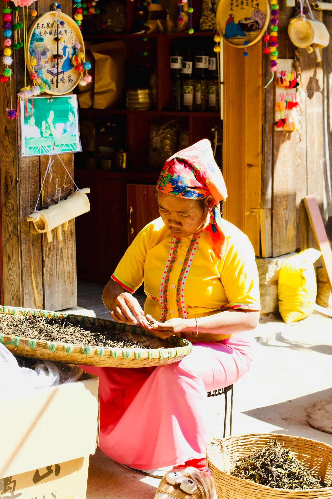 A Bulang woman sorting tea leaves at the front of her shop