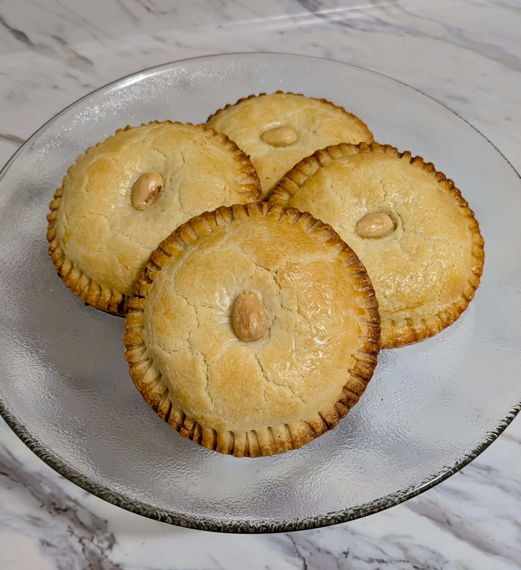 Four Gevulde Koeken pastries stacked on top of each other on a glass plate.
