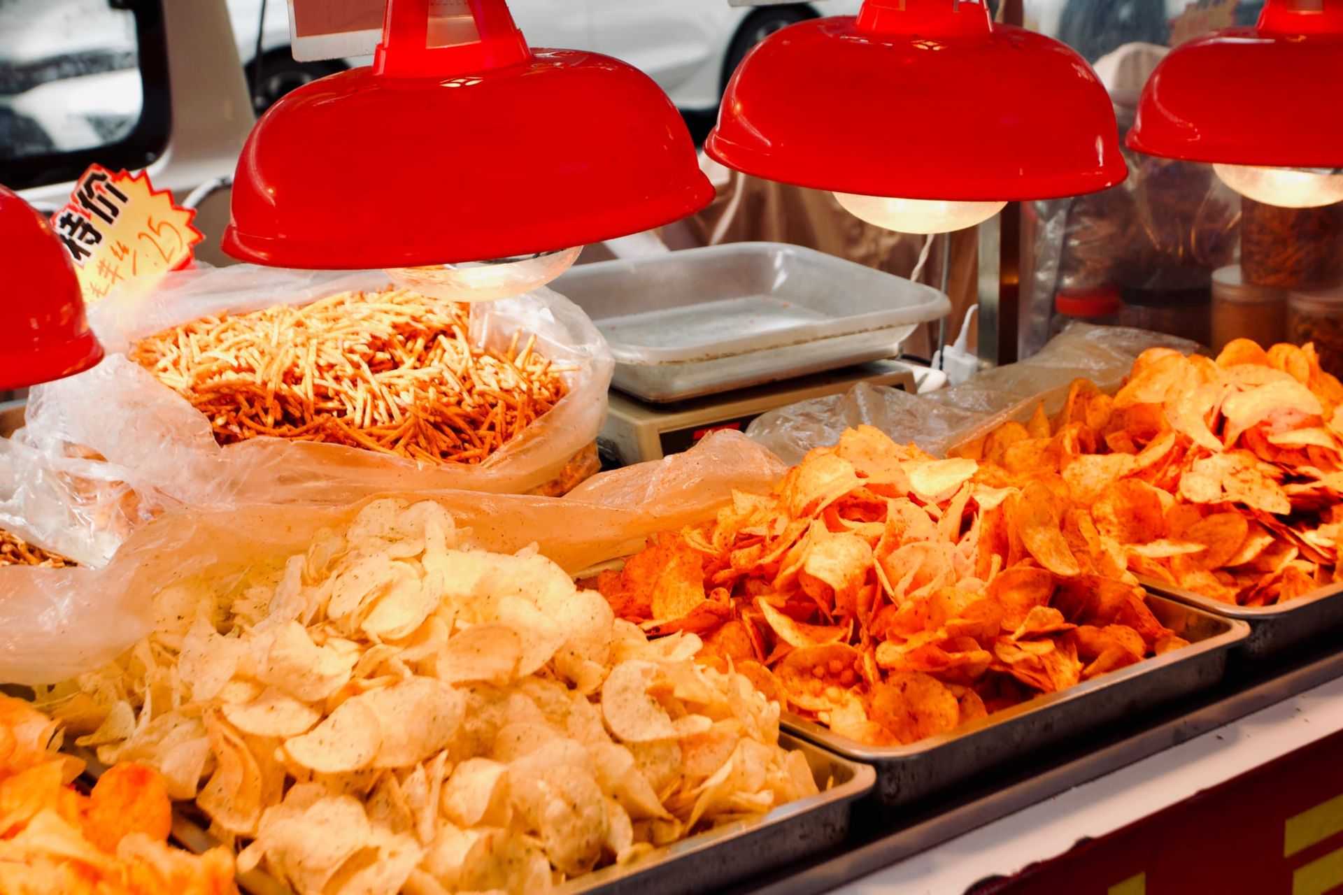 A series of red heat lamps warms trays of different flavored potato chips.