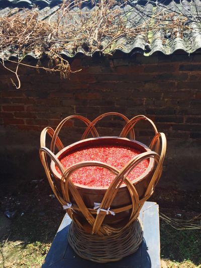 A large brown bamboo bowl filled with ground red chili peppers.