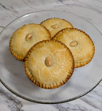 Four Gevulde Koeken pastries stacked on top of each other on a glass plate.