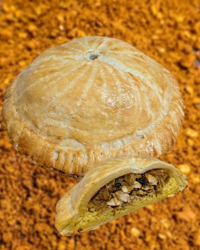 Sri Lankan Chicken Curry Pithivier, one whole, one sliced in half to show the cross section. A flaky golden pastry stuffed with chicken, rice, and onions.
