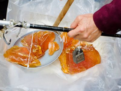 Large amber glass-like rocks on an old-fashioned weighing rod with a 1.0kg weight on the end