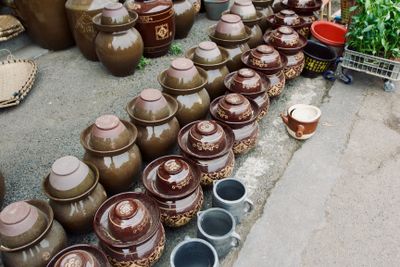 Two rows of small, 12'' brown ceramic pickling jars - one row is plain, the other has a decorative pattern painted on the side.
