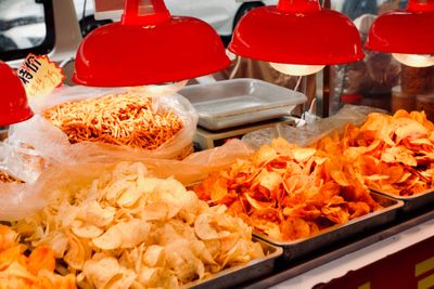A series of red heat lamps warms trays of different flavored potato chips.