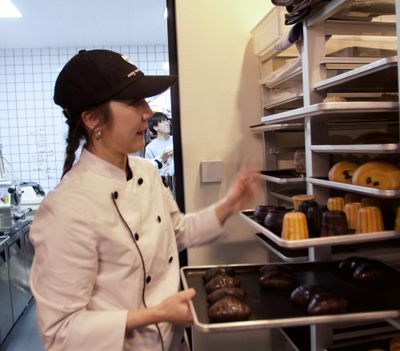 Ally Jiang pulling bakery trays from their rack, each filled with laminated pastries.