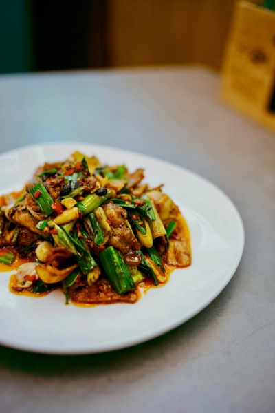 A white plate with stirfried meat and green vegetables in an orange-brown sauce.