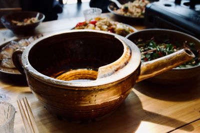 A brown clay teapot-like pot with a wide open top is filled with clear liquid - Guizhou rice wine.