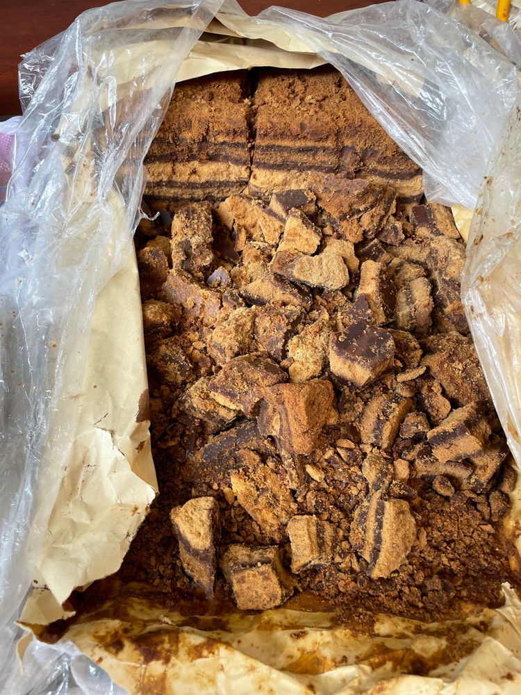 Traditional brown sugar in a bag in a market, layers of different shades of brown can be seen on the various pieces broken and smashed up in the bag.