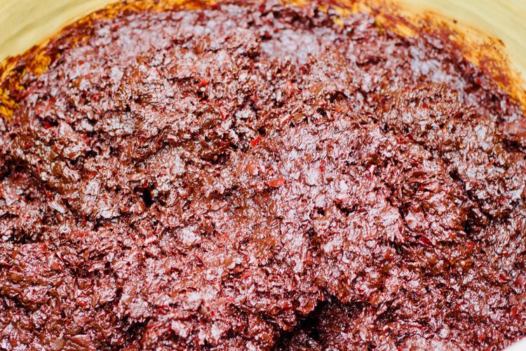A close up photo of the red doubanjiang dish in a giant urn.