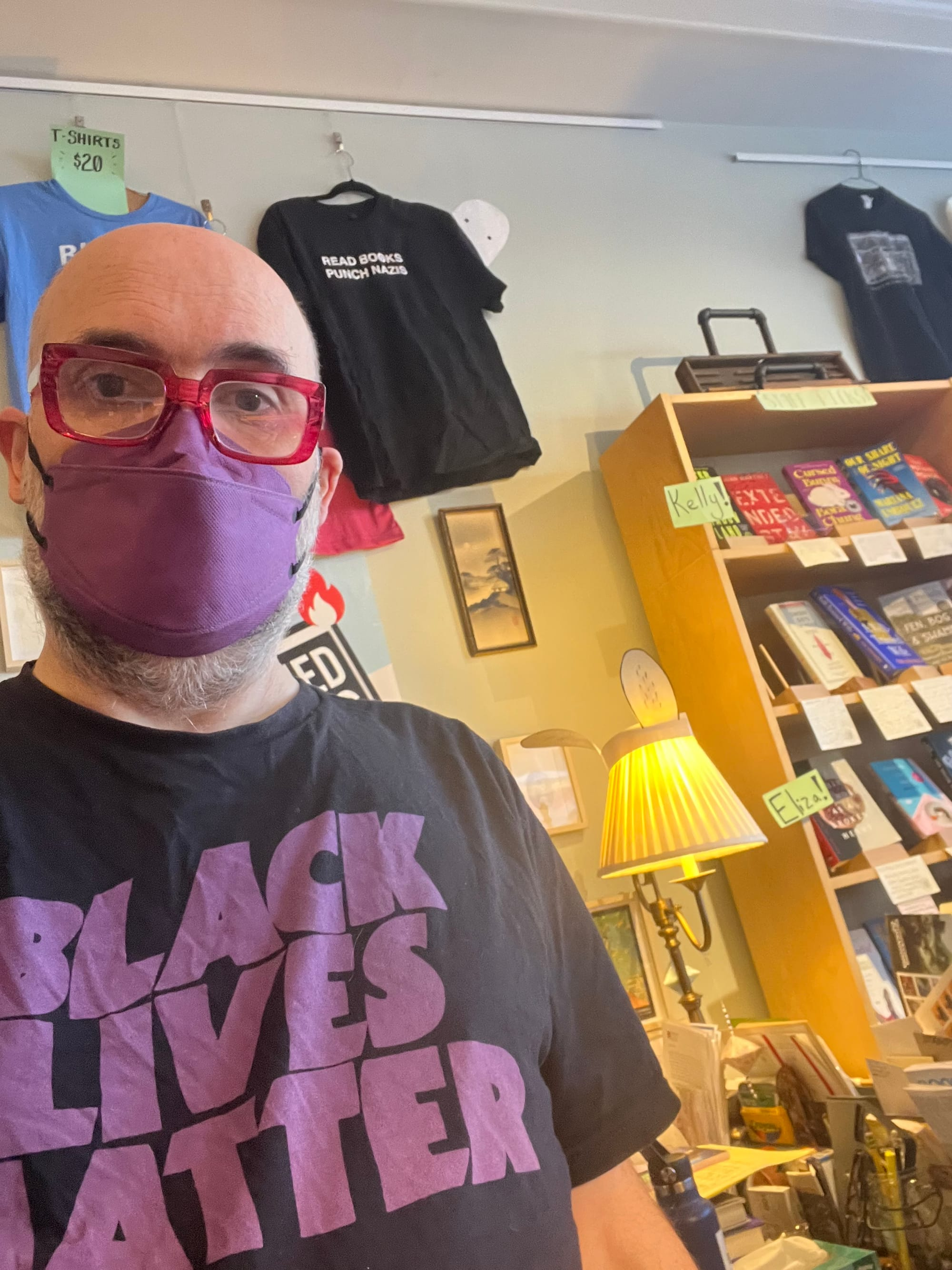 Gavin wearing a purple KN95 mask and a Black Lives Matter T-shirt with purple lettering. Books visible in the background.