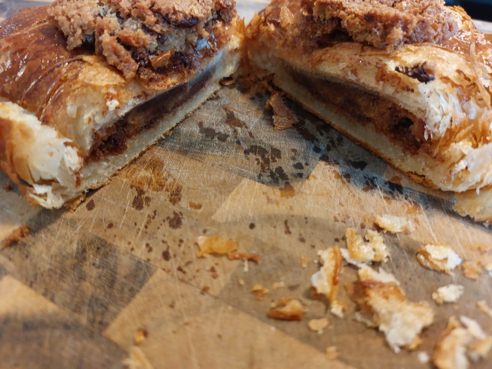 Croissant cut open on cutting board, with two halves parted to show the inside, where the cookie has transformed into something akin to a pie filling