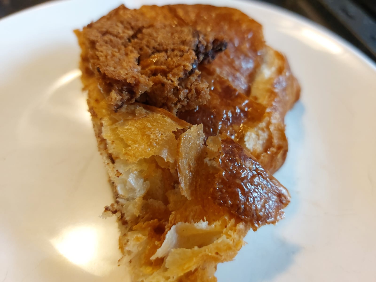 Top-down, angled frontal view of the finished "crookie" product on white plate, showing that it looks flaky and delectable despite essentially being some cookie mashed together with some croissant that was toasted for a few minutes