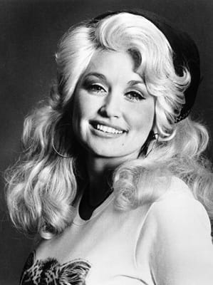 Black and white photo of Dolly Parton as a young woman, smiling at the camera