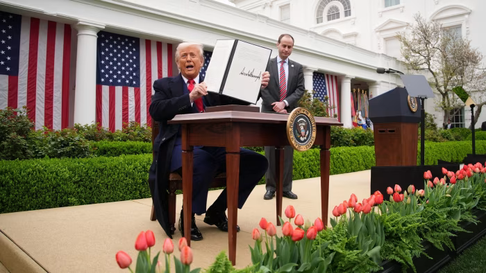 US President Donald Trump displays a signed executive order from a desk in the Rose Garden