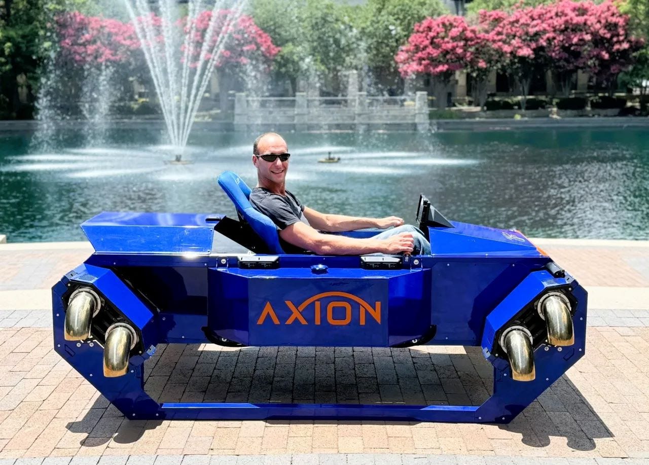 A man sits in the Axion personal vertical takeoff and landing vehicle from FusionFlight. The vehicle is blue 