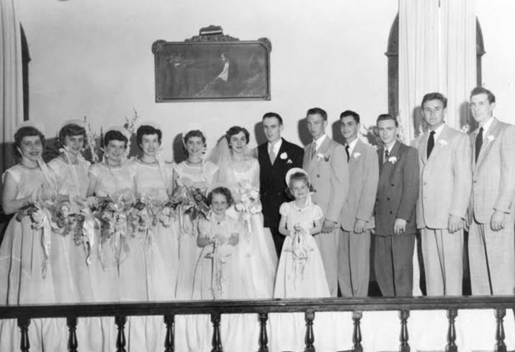 A black and white photo of a large wedding party from 1950, with a very young Gene Hackman serving as one of five groomsmen