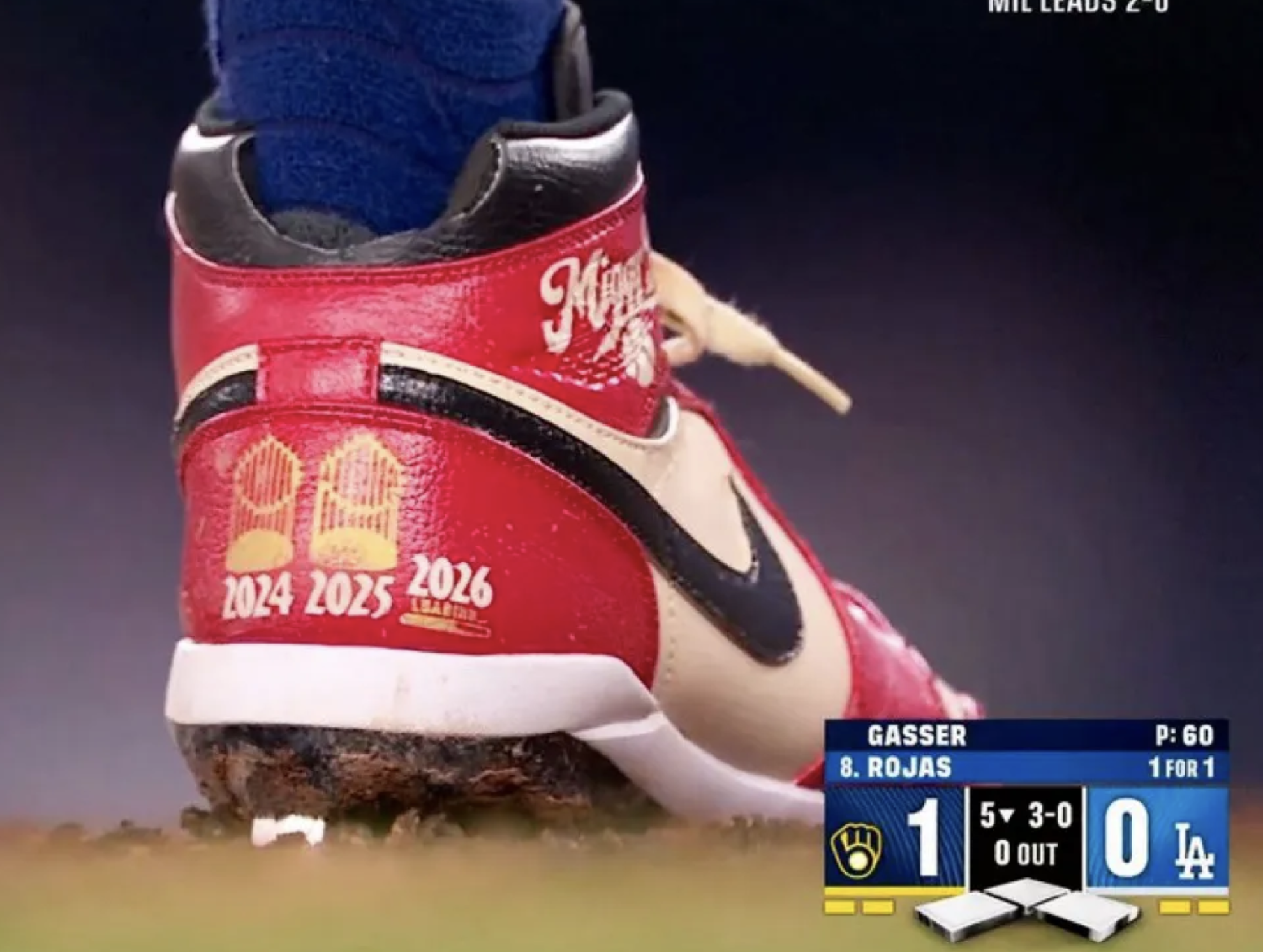 Miguel Rojas' cleat, caught on the fox camera. On the heel it has two images of the World Series trophy over "2024" and "2025." There's a blank space above "2026," in clear anticipation of the Dodgers winning it again.
