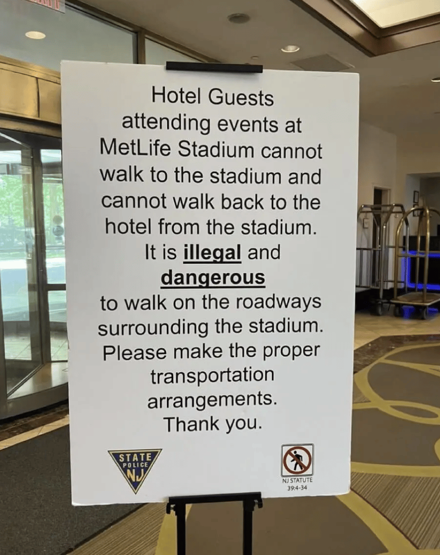 sign in hotel lobby saying "Guests attending events at Met Life Stadium cannot walk to the stadium and cannot walk back to the hotel from the stadium. it is ILLEGAL and DANGEROURS to walk on the roadways surrrounding th stadium. Please make the proper transportation arrangements" 