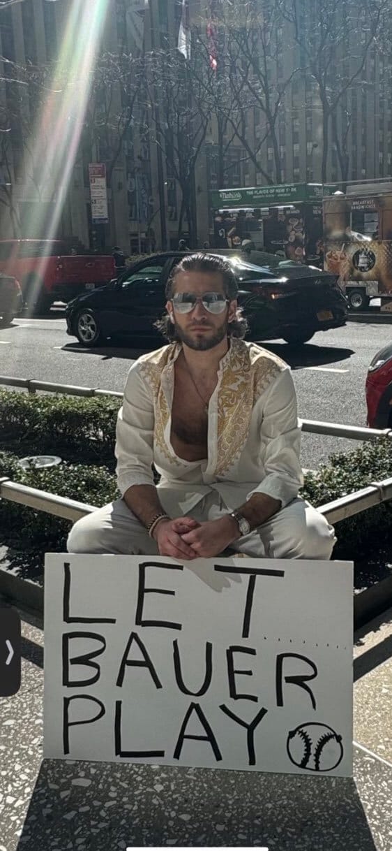 A total douchebag holding a sign that says "Let Bauer Play"