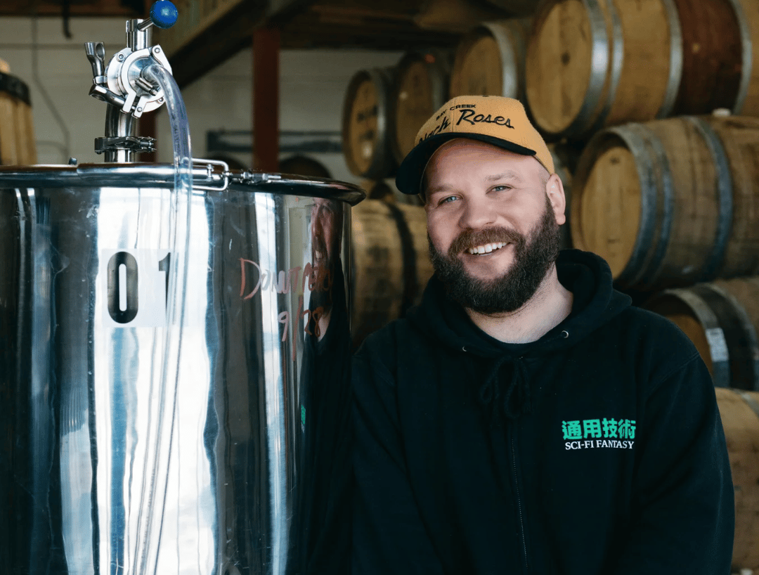Photo of the smiling owner of a brewery from the brewery website, guy is wearing the same cap as in the security photos