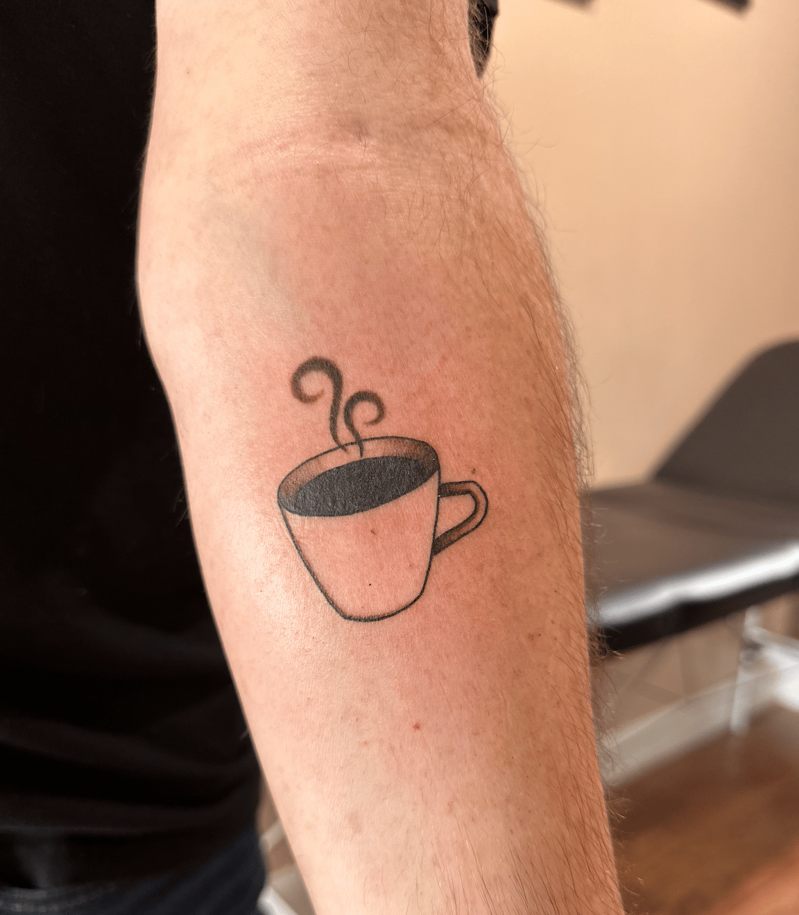 A tattoo of a cup of black coffee on my forearm