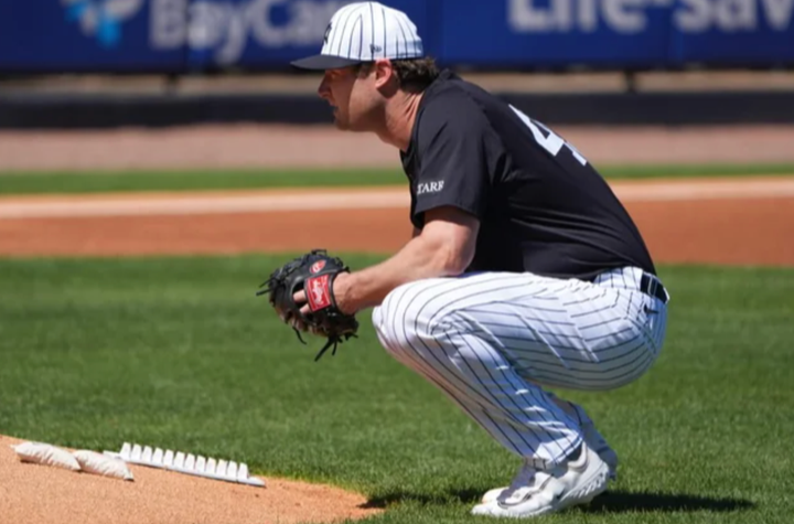 Gerrit Cole in a spring training uniform crouching behind the mound