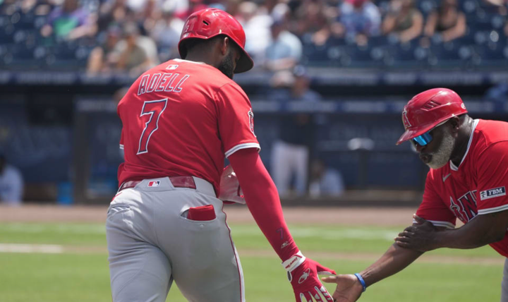 Jo Adell rounding the bases and giving the first base coach a low-five after hitting a home run