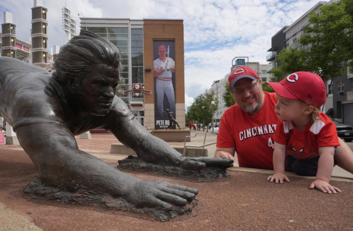 A man and his one-year-old son stand next to the Pete Rose statue at Great American Ballpark