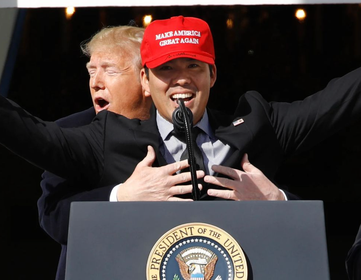 Kurt Suzuki, wearing a MAGA hat, his arms up in the air in triumph, while being hugged from behind by Donald Trump