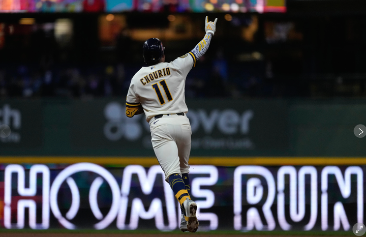 Jackson Churio rounding the bases, arm up, in front of a "Home Run" sign