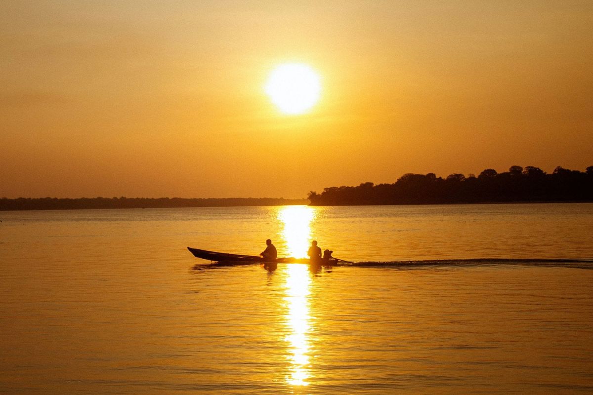 Two men in a boat at sunset on the Amazon river