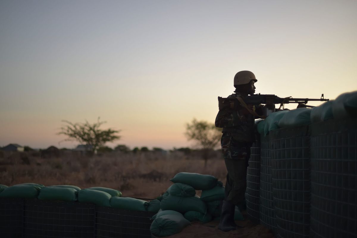 Soldier looking over a barricade at sunset