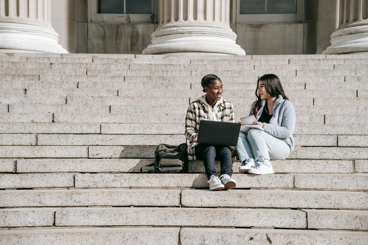 Two students sitting on outside steps. 