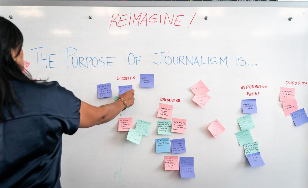 A woman placing sticky notes with words on them on a whiteboard