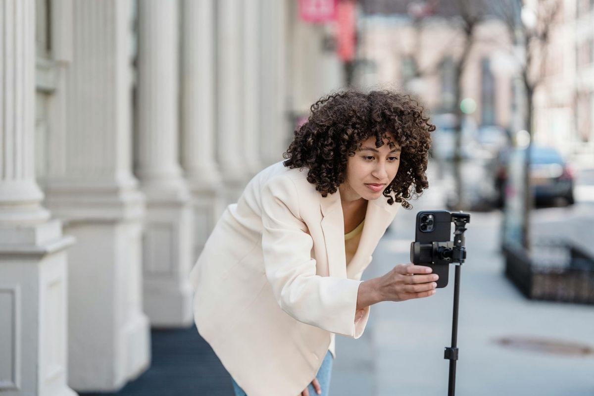 A woman setting up her phone on a tripod to record a video.