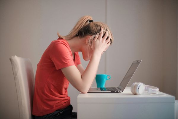 Woman with her head in her hands looking at a computer
