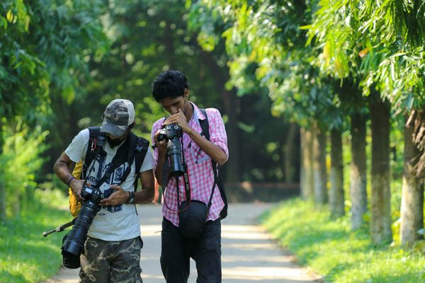 Two men looking at their cameras while in nature.
