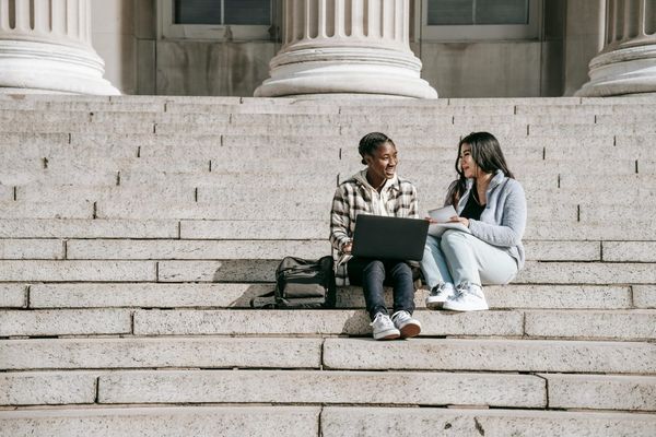 Two students sitting on outside steps. 