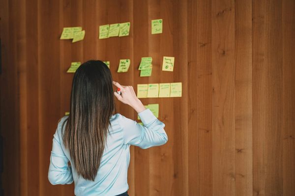 A woman looking at text on sticky notes on a wall.