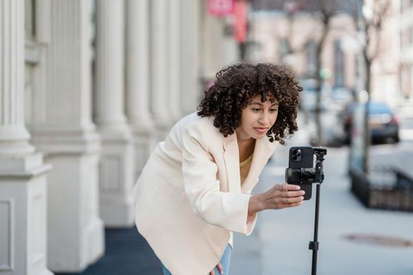 A woman setting up her phone on a tripod to record a video.
