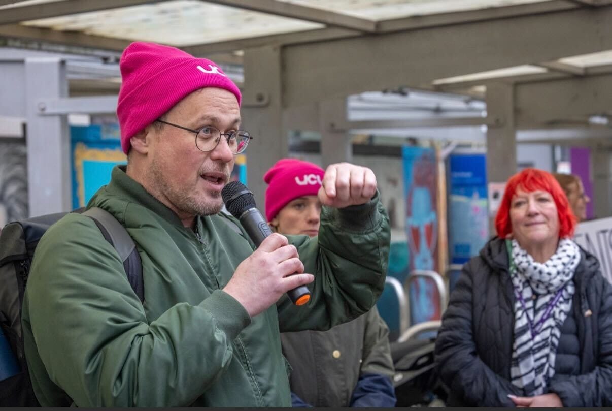 Mark wearing a UCU beanie holding a microphone