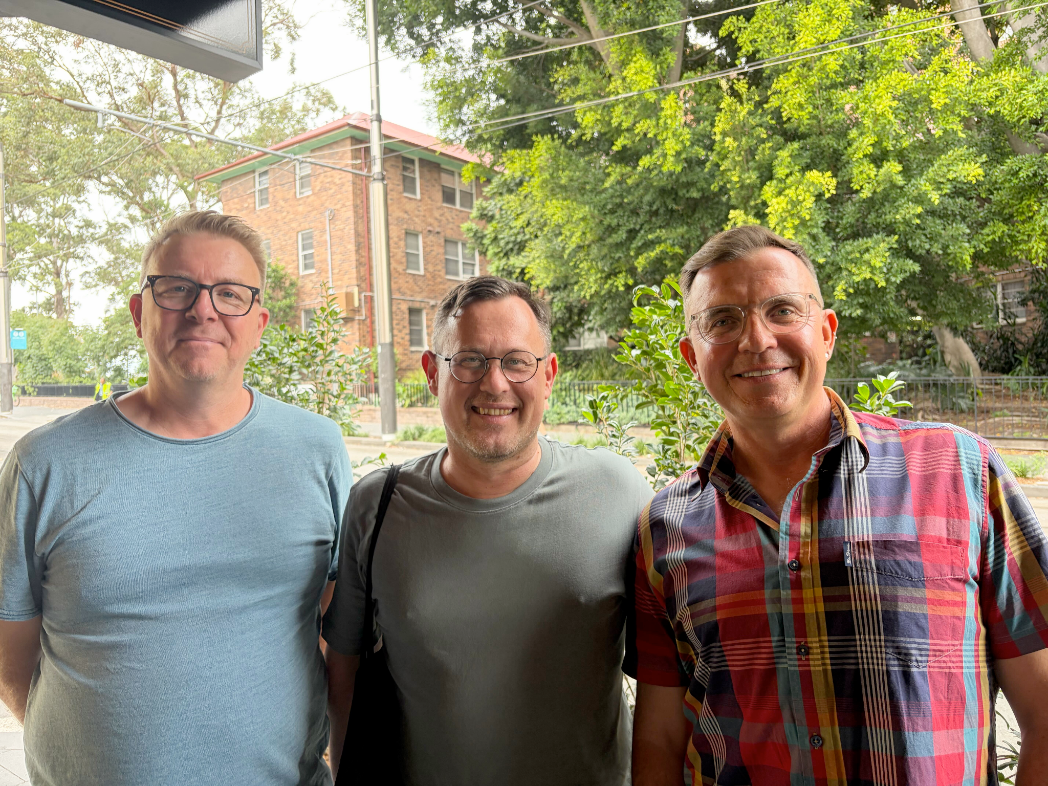 Three white men with glasses smiling to camera