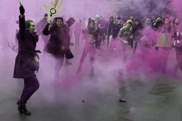 Strikers dance at a rally in amongst the purple smoke of a smoke bomb. 