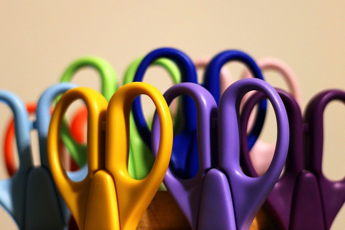 Pairs of scissors with handles in various colours including yellow, purple, blue and green. 