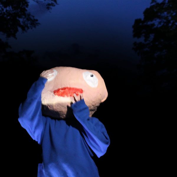 the cover for Space Camp's album, how could i not be your girl? The cover is someone in a blue sweatshirt with a giant, eerie paper machie head against the dark night sky.