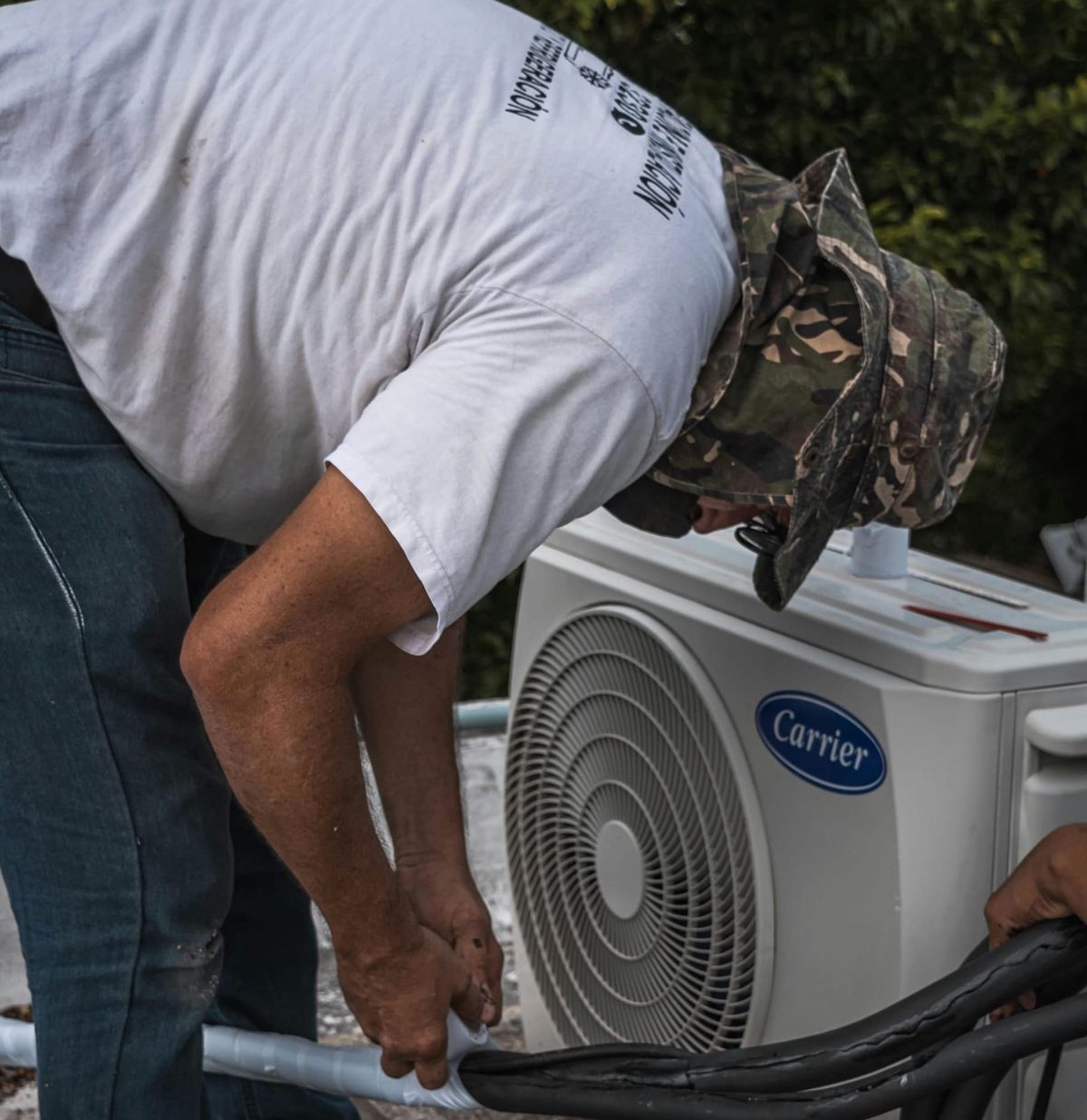 A man installing an air conditioner outside.